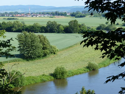 Bild vergrößern: Zu sehen ist ein Foto des Landkreises Hameln-Pyrmont auf dem im Vordergrund die Weser zu sehen ist und im Hintergrund Felder, Wiesen und Häuser