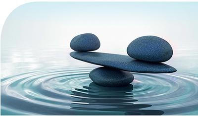 Bild vergrößern: Zu sehen sind im Wasser aufgestapelte Steine, die eine ausgeglichene Waage symbolisieren.